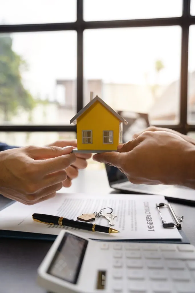 Hands holding a model home during a property agreement
